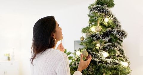 Woman Decorating Elegant Christmas Tree at Home