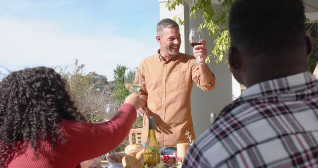 Happy caucasian man toasting on thanksgiving celebration meal in sunny garden. Celebration, friendship, patriotism, american culture and tradition, unaltered.