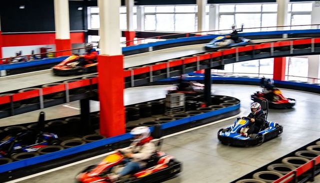 Indoor go-kart racing on two-level track high-speed action driver in blue kart helmet