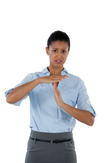 Businesswoman in office attire making a timeout hand gesture, expressing frustration or need for a break. Useful for illustrating workplace stress, conflict resolution, or communication in professional settings.