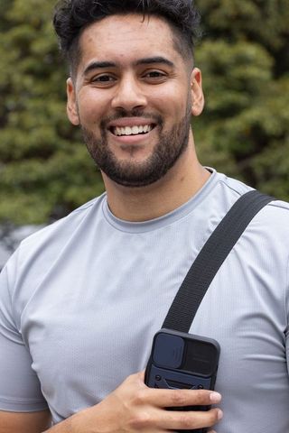 Smiling african american man holding handheld gadget wearing gray athletic shirt outdoors