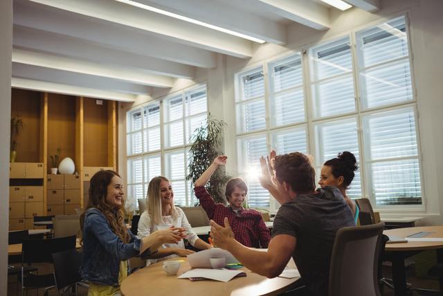 Group of happy business executives giving high five in office