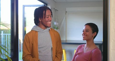 Sunlit african american couple chatting by glass door in modern kitchen entry