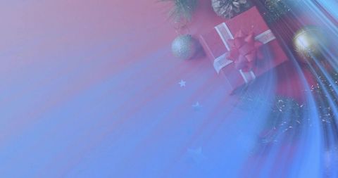 Festive red gift box with white ribbon, baubles and pinecone on blue-red gradient