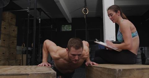 Trainer supervising athlete doing push-ups on plyometric boxes