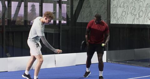 Diverse men practicing padel on blue court