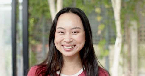 Cheerful Asian Woman Smiling Against Lush Background