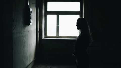 Silhouette of Woman Standing Near Large Window