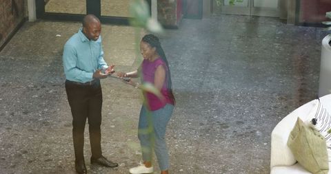 Joyful colleague interaction with tablet in modern office corridor