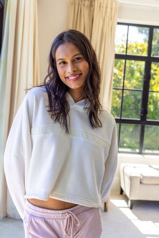 Smiling african american woman wearing hoodie and pink sweats in sunlit modern living room
