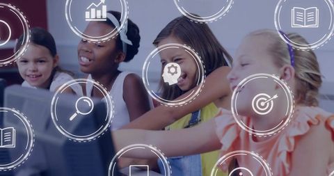 Schoolgirls collaborating on classroom computers learning digital skills and teamwork
