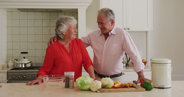 Shows an elderly couple preparing a meal together in a bright kitchen, transferring a happy and healthy lifestyle for seniors. Ideal for websites or brochures focusing on senior living, senior activities, healthy eating, family values, and home cooking inspirations.