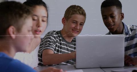 Teen students collaborating on laptop in classroom during group learning session