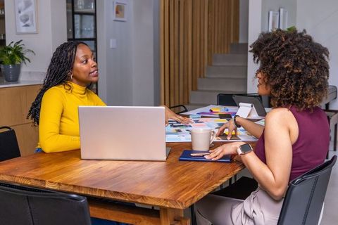 African American Women Collaborating on Design Layouts and Color Swatches at Home Workspace