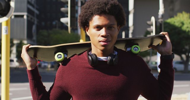 Portrait of african american man in city, standing holding skateboard on shoulders and smiling - Download Free Stock Photos Pikwizard.com