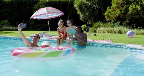 Friends enjoying poolside fun with inflatable ring on sunny day