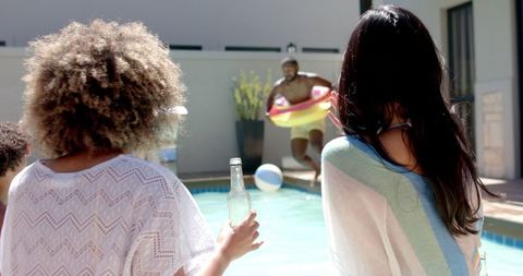 Friends Cheering by Pool as Man with Inflatable Ring Jumps In - Download Free Stock Images Pikwizard.com