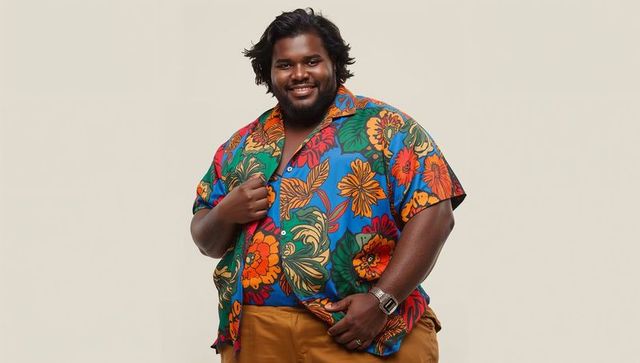 Smiling indian man wearing vibrant floral shirt and mustard pants, posing confidently