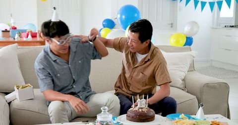 Young man receiving surprise birthday gift from friend at celebration