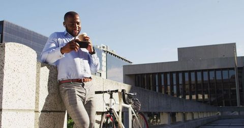 Man Enjoying Coffee and Smartphone Break by Bicycle in Urban Setting