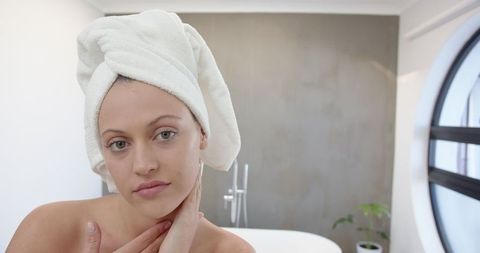 Woman Wrapping Hair in Towel Inside Modern Bathroom with Minimalist Interior