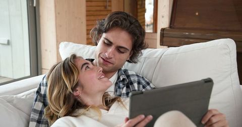 Couple relaxing with tablet on sofa in cozy living room