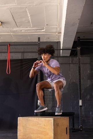 African american athlete performing plyometric box jump in urban gym for explosive power