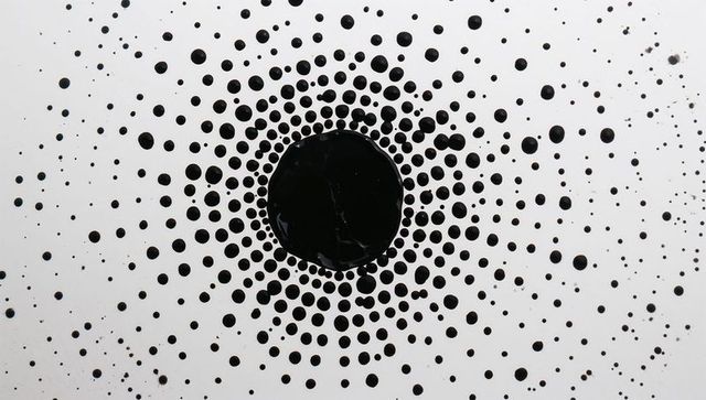 Radiating black ink dots forming concentric circular pattern on white background