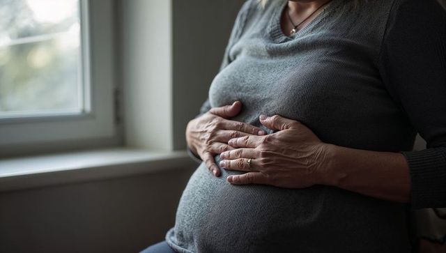 Expectant woman cradling pregnant belly by window, serene intimate maternity moment