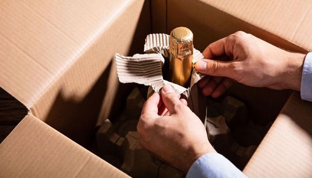 Unwrapping champagne from cardboard box showing protective packaging and secure handling