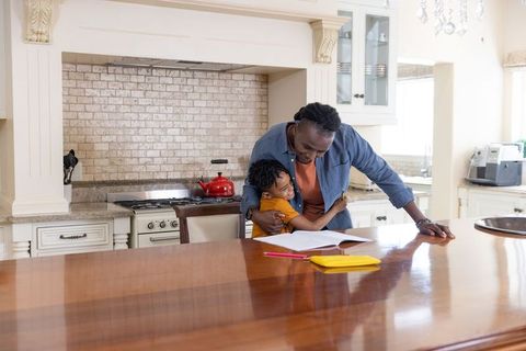 African american father helping son with homework on kitchen island family bonding
