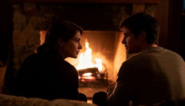 Couple sitting by fireplace sharing quiet conversation during cozy winter evening at home