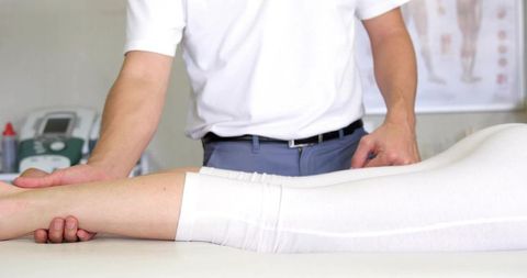 Physiotherapist assessing lower leg mobility during rehabilitation session