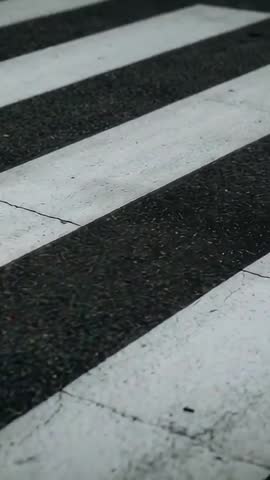 Vertical pushing shot revealing painted crosswalk on cracked asphalt over zebra stripes