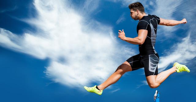 Male athlete dynamically jumping over hurdles with a blue sky background, showcasing athleticism and energy. Perfect for use in sports-related content, motivational materials, fitness advertising, and promotional campaigns for athletic wear or training programs.