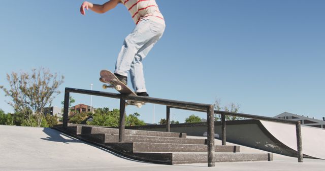 Low section of caucasian man riding and jumping on skateboard on sunny day. hanging out at skatepark in summer.