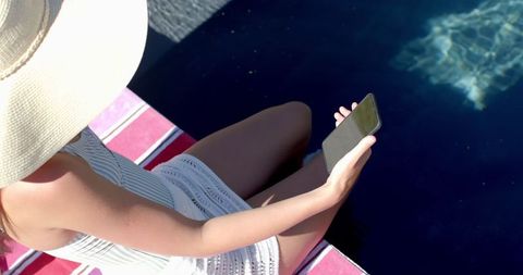 Teenage Girl Relaxing by Pool Using Smartphone