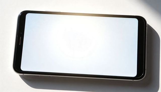 Minimal lying smartphone with blank white screen and glare for app mockups and ui