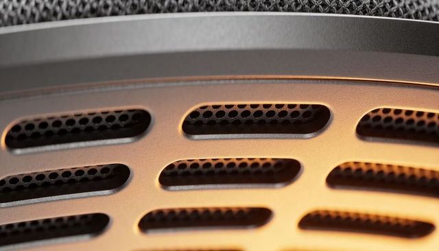 Showing warm-lit metallic grille with elongated oval vents and honeycomb mesh macro