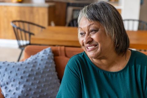 Smiling african american senior woman relaxing at home on orange sofa
