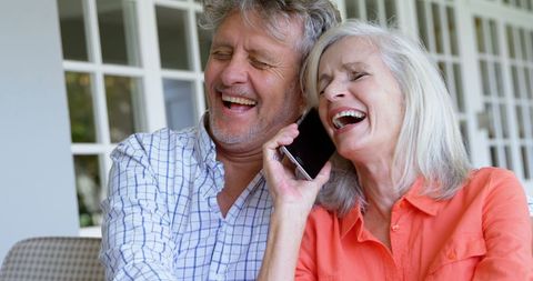 Happy Senior Couple Embracing and Using Smartphone Together