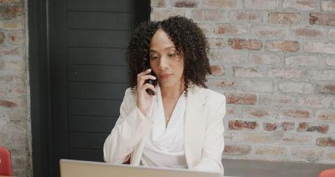Businesswoman Managing Calls and Laptop in Office