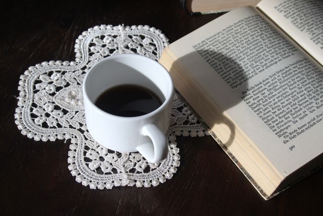 Coziness with Open Book and Cup of Coffee on Lace Doily - Download Free Stock Photos Pikwizard.com