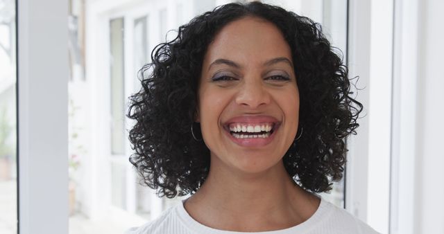 Happy Woman with Curly Hair Smiling in Bright Room - Download Free Stock Images Pikwizard.com