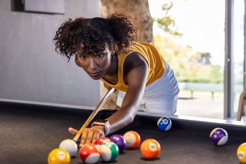 Young woman aiming pool shot in bright game room focusing on precision and leisure