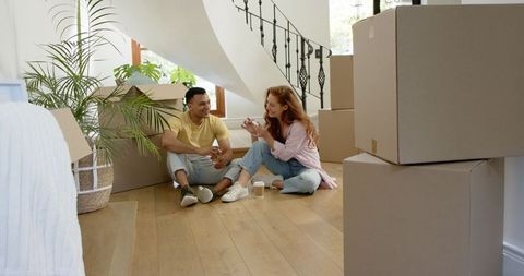 Couple Smiling in New Home Amidst Cardboard Boxes, Planning Move