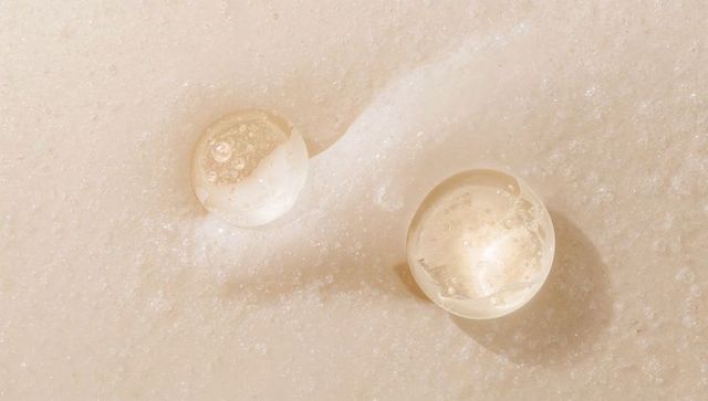 Clear gel droplets on cream foam showing microbubbles macro skincare texture