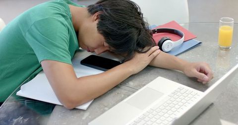 Exhausted Student Sleeping by Open Laptop with Study Materials