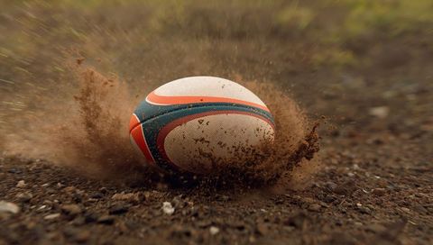Rugby ball rolling on dusty field with dynamic energy