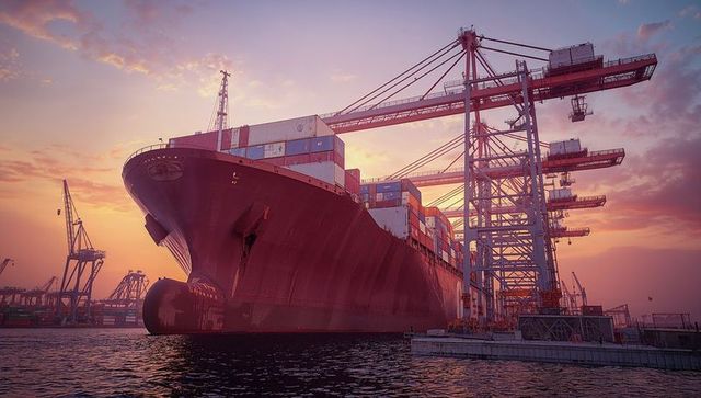 Gantry cranes loading container ship at sunset in port